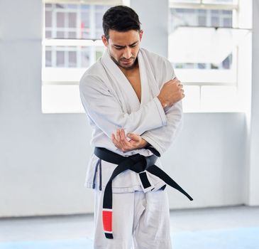 Karate, arm pain and man with injury in dojo, healthcare and fighting. Sports, fitness and martial arts fighter in India with hand elbow sports injury and medical emergency in fighting gym or studio.
