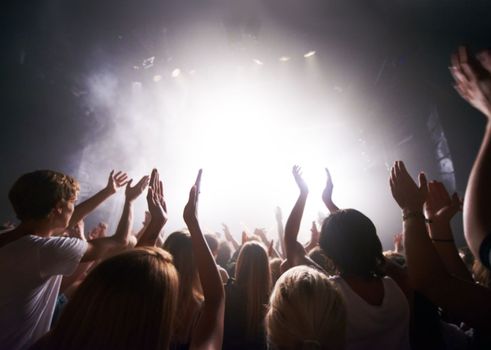Concert, live music and people dancing at an event, party or nightclub with energy, freedom and fun. Band, musician or dj entertainment playing at music festival or rave at indoor venue with a crowd.