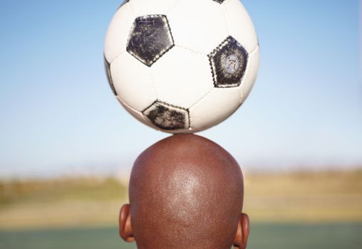 Balance and skill. Cropped rearview image of a man balancing a soccer ball on his head.