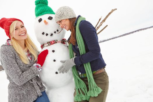 Women, snow and building a snowman in winter during Christmas while having fun and bonding. Friendship, winter and xmas or festive season with ladies creating a frozen snow man in cold weather