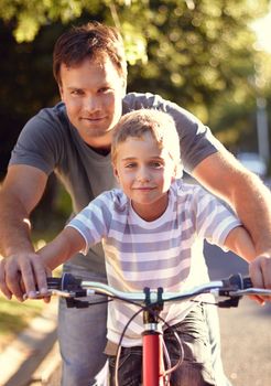 Learning from the best. a father and son spending quality time together with a bicycle