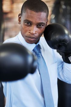 The business world is a harsh place. A young african american boxer in a shirt and tie throwing a punch at you.