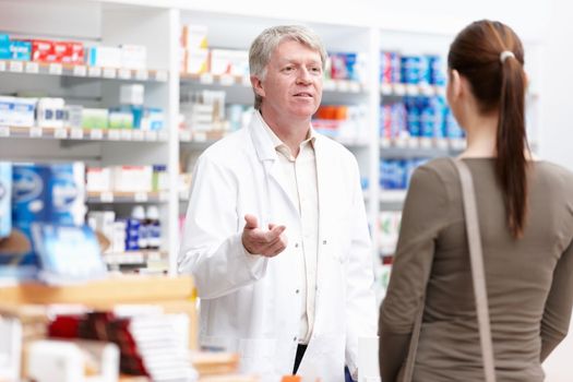 Male pharmacist speaking with customer. Portrait of happy male pharmacist speaking with customer at drugstore.