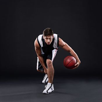 The spirit of a true champion. Full length portrait of a male basketball player in action against a black background.