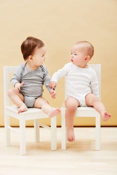 Making new friends. Adorable shot of two cute babies sitting on chairs and smiling at each other.