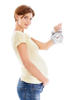 Its nearly time...A beautiful pregnant woman showing you a clock while isolated on a white background.