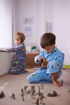 Parallel play. Two brothers sitting on the floor playing separately with their toys.