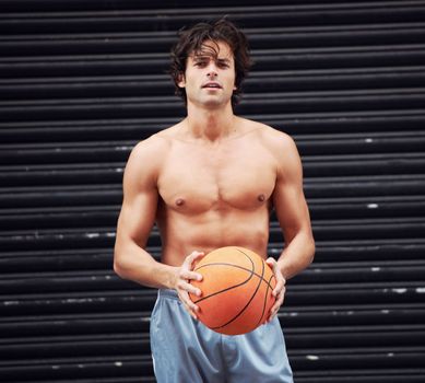Basketball or nothing at all. A handsome athletic man sitting outside holding a basketball.