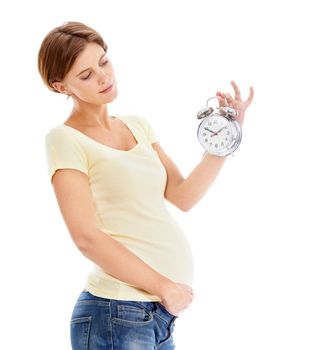 Counting down the time until the baby arrives. A pretty pregnant woman holding a clock while isolated on a white background.