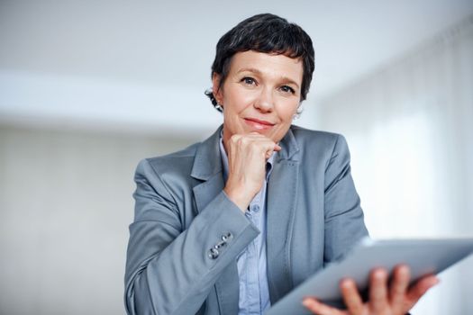 Successful business woman using tablet PC. Portrait of successful mature business woman using tablet PC in office.