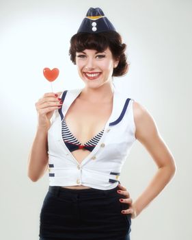 50s romance. Studio shot of a retro-dressed model holding a heart-shaped lollipop.