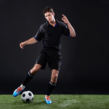 Going for the goal. a handsome soccer player isolated on black.