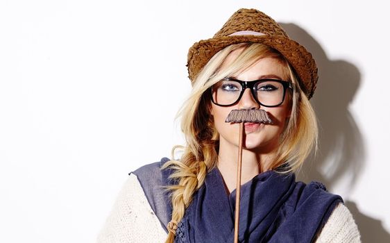 Howd you like my moustache. Cropped studio portrait of a young female hipster holding a moustache prop to her face.
