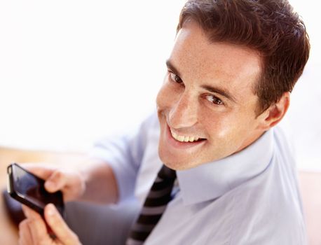 Sending a text to a valuable client. Smiling young businessman sending a text message.