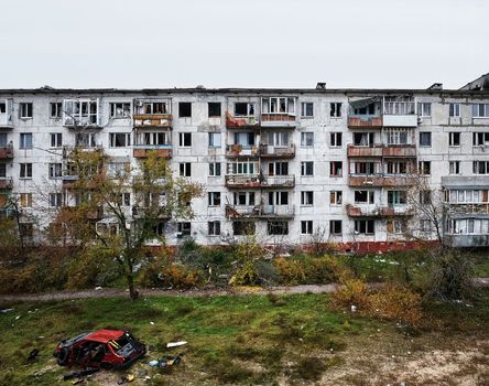 The yard of destroyed apartment buildings in the war zone. Damage to a house as a result of artillery shelling. War in residential areas, broken windows and burned apartments. Armed conflict in Ukraine.