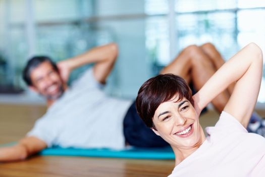 Man and woman doing yoga. Attractive woman in stretching pose with man in background.