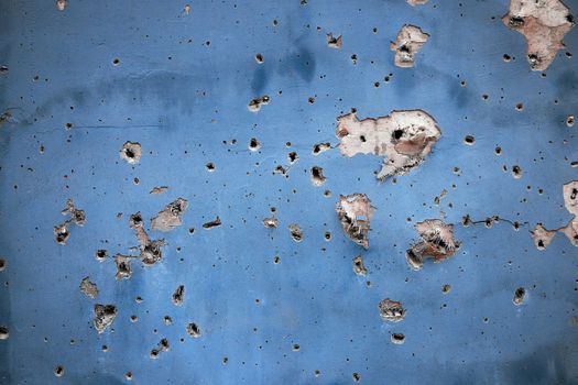 Holes from artillery shell fragments in the wall of an apartment building. Damage to a residential building as a result of artillery shelling. War in residential areas. Armed conflict in Ukraine