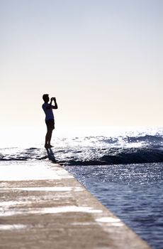 Hes one with the ocean. Full-length concept shot of a young man standing on a wave.