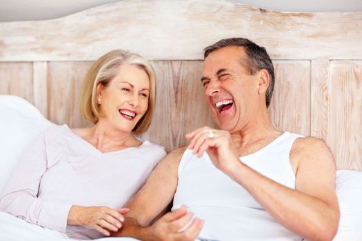 Cheerful mature couple having fun in bed. Portrait of a cheerful mature couple having fun in bed.