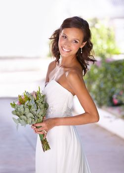 Feeling beautiful on her wedding day. Beautiful young bride holding her bouquet.
