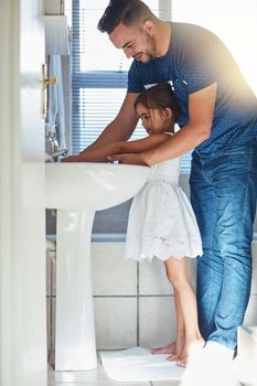 Lets wash those germs away. a father helping his little daughter wash her hands at the bathroom sink.