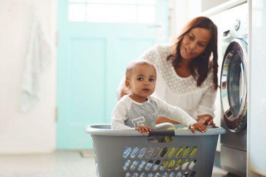 I hope she doesnt mix me with the other colors. a mother and her adorable baby boy doing the laundry at home.