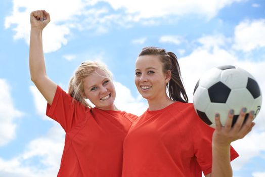 Celebrating another win. Portrait of two young female soccer players standing on a soccer field.