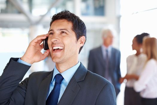 Business man on call with executives discussing. Portrait of cheerful business man on call with executives conversing in background.
