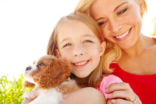 The perfect addition to any family. a mother, daughter and puppy at bliss in the Outdoors with copyspace.