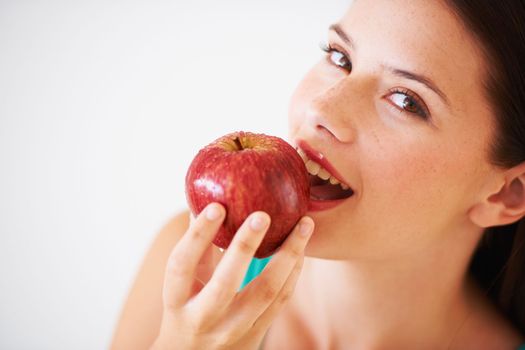 Eating a crunchy red apple. Portrait of an attractive young woman enjoying an apple.