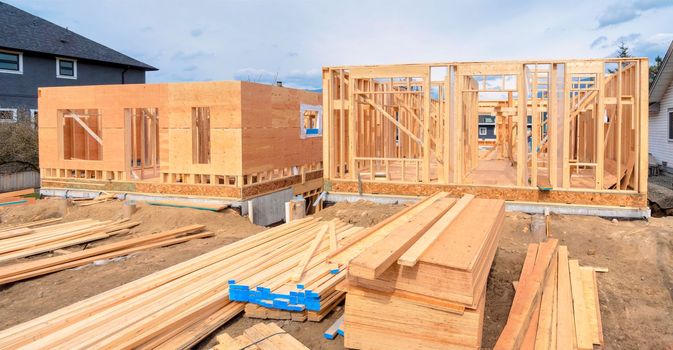 Wooden frame of two new houses with engineered lumber materials in front