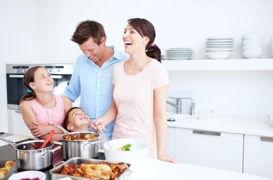 Laughter and love in the kitchen. A happy family cooking a large, delicious meal together in the kitchen - Copyspace.