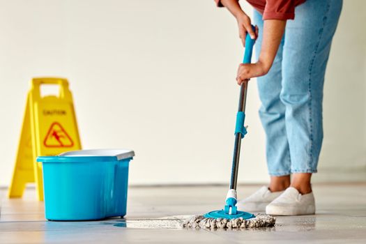 Cleaning, sign and woman mopping floor in office for hygiene, health and wellness. Spring cleaning, service and janitor, cleaner and female with mop, water bucket and caution wet floor warning notice