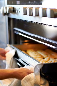 Nothing like that fresh bread smell. someone taking freshly-baked goods out of an oven.