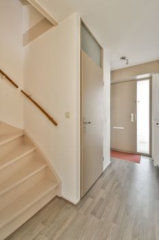 a hallway with white walls and stairs and a door
