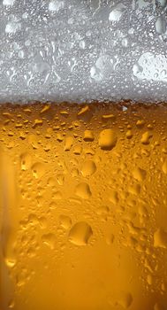 White foam and condensation on a glass of cold beer