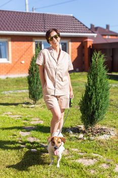 Young woman wearing pajama with her dog on backyard. The concept of animals and friendship or pet owner and love