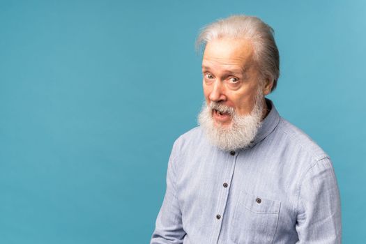 Portrait of shocked old man wear casual cloth open mouth isolated on blue color background with copy space - elderly people and emotion concept