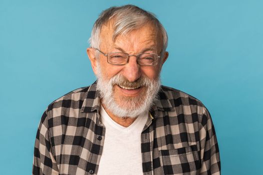 Close-up portrait retired old man with white hair and beard laughter excited over blue color background