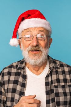 Portrait of shocked old man wear santa christmas hat open mouth isolated on blue color background - elderly people and emotion