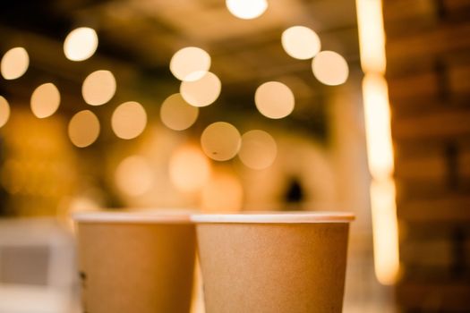 Close up two cardboard coffee cups take away on table over bokeh background - coffee shop and take away drink concept