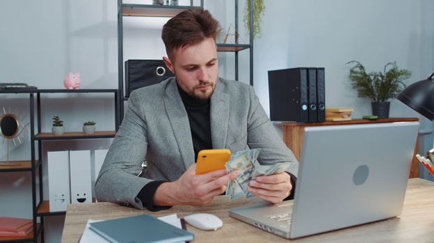Rich businessman in suit working on smartphone counting money cash, calculate earnings income profit