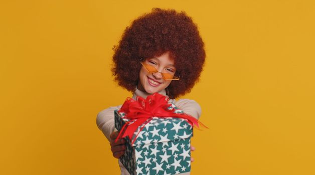Lovely smiling teen child girl kid presenting birthday gift box offer wrapped present celebrating