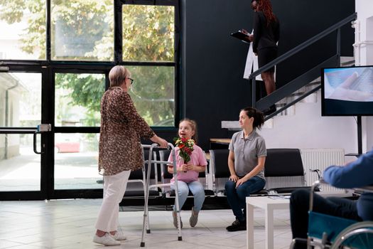Granddaughter giving flowers to grandmother after finishing medical examination