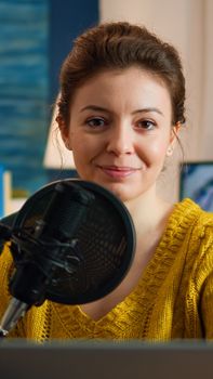 Woman blogger sitting in home studio looking at camera