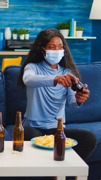 Mixed race women with protection mask playing video game