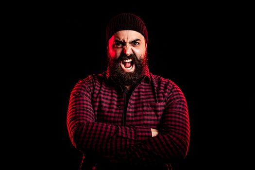 Bearded man screaming in anger on black background
