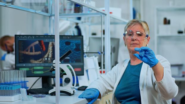 Senior woman lab technician looking at virus sample