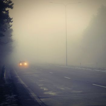 Bad weather driving - foggy hazy country road. Motorway - road traffic. Winter time.