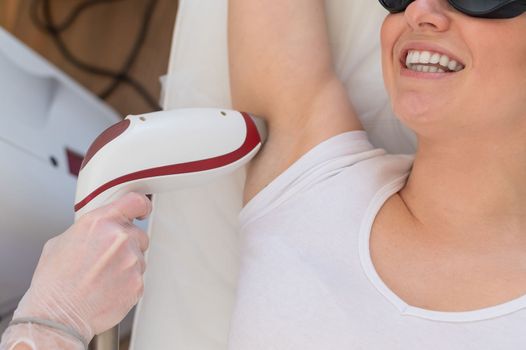 Doctor doing laser hair removal on a woman's armpit in the salon. An alternative way to permanently remove unwanted body hair